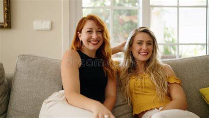 two women sitting on a couch in a living room
